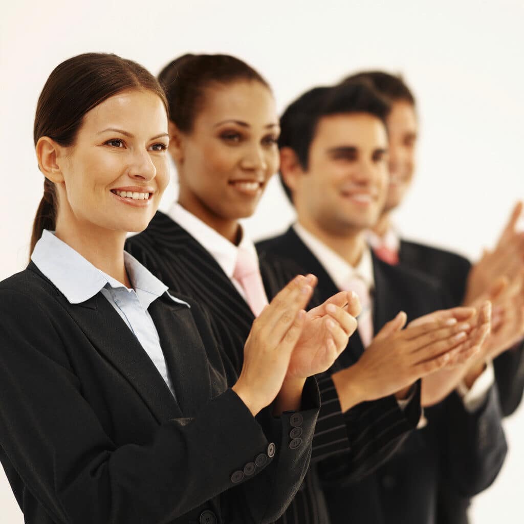 Close-up of four business executives standing in a line and applauding --- Image by © Royalty-Free/Corbis