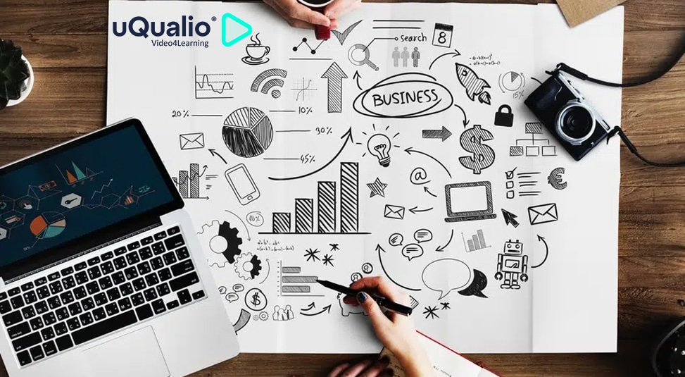 5 Things to Look for in an eLearning Solution|Two people at desk drawing business related symbols uqualio logo